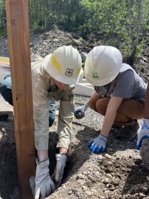 A U.S. Forest Service worker and a Greenway Trust intern work to add a sign to the Franklin Falls Trailhead