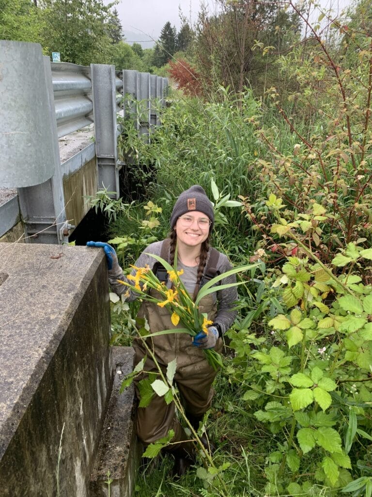 Leah Grimmer stands inside of a bush next to a bridge