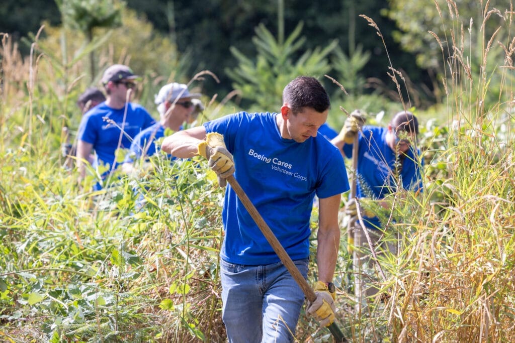 Corporate team volunteer with "Boeing Cares" shirts on working to restore a habitat